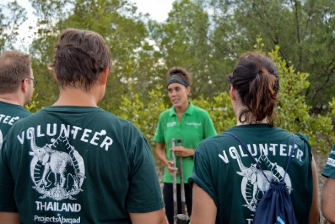 A Conservation project staff member explains mangrove reforestation to volunteers in Thailand