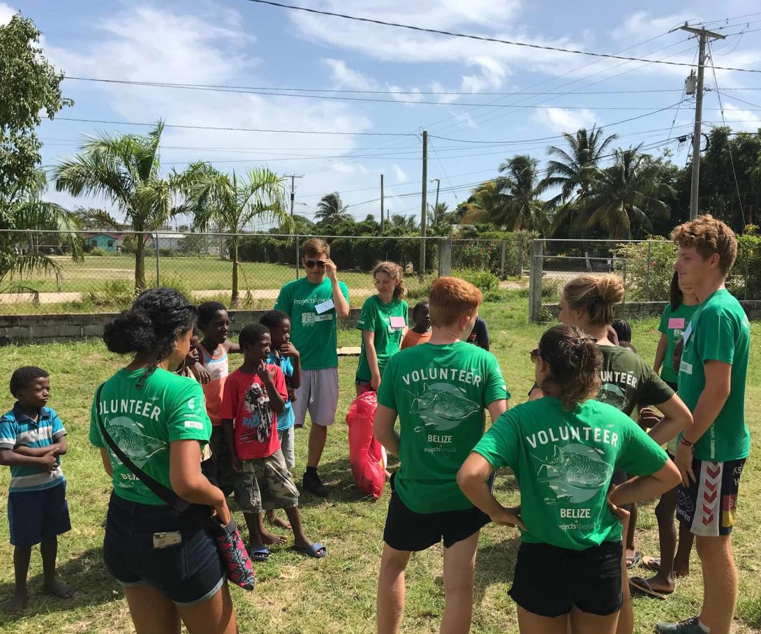 High school students volunteering in Belize explain a litter and recycling awareness activity to children at a summer camp.