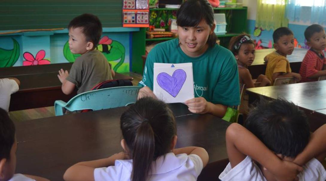 A Projects Abroad volunteer showing Filipino children a purple heart as part of identifying basic shapes