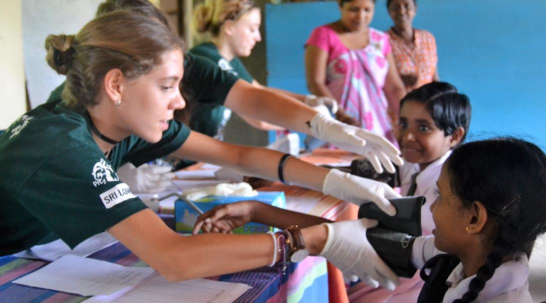 A clinical volunteer abroad measures the blood pressure of a young child in Sri Lanka.