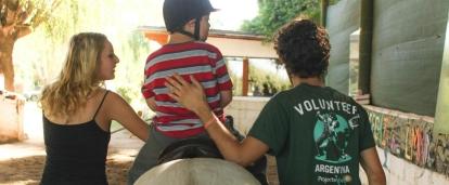 Projects Abroad interns doing an Equine Therapy placement in Argentina help a child ride a horse during a therapy session.