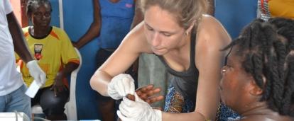 Female Medical intern treats a local woman's finger at a Public Health Outreach programme during her Medical placement in Ghana.