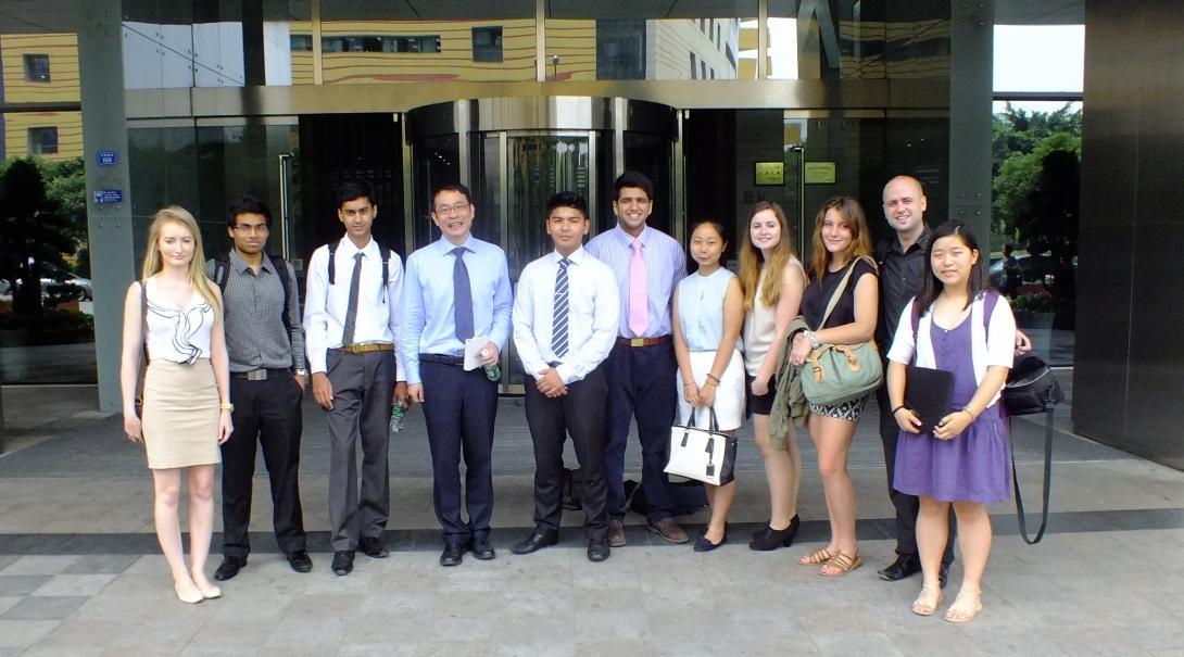 International business interns and local professionals pose outside a modern office block.