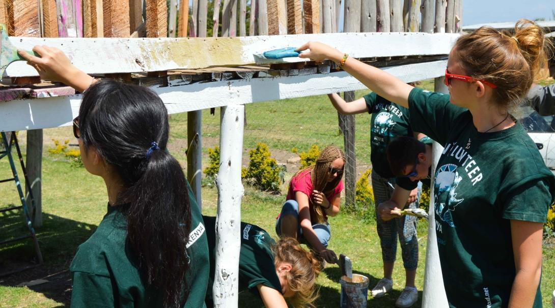 Volunteers paint a jungle gym in Kenya on a volunteer abroad program for 17 year olds. 