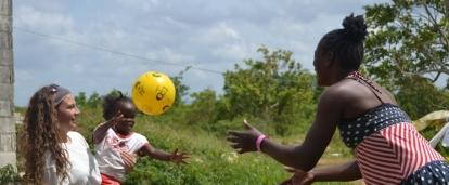 A volunteer working with children in Jamaica does an activity with a ball to improve hand-eye coordination at our Childcare Project.