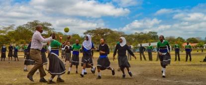 Volunteers coaching sports in schools in Tanzania play a ball game with students.