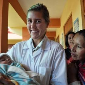 A student doing her Midwifery internship abroad holds a new-born infant at a local hospital.