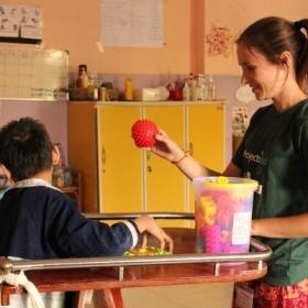 A disabled child does basic exercises using a ball with a student doing an Occupational Therapy internship abroad.