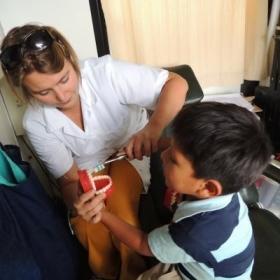 A young boy learns how to brush his teeth correctly with the help of a student doing a Dentistry internship abroad.