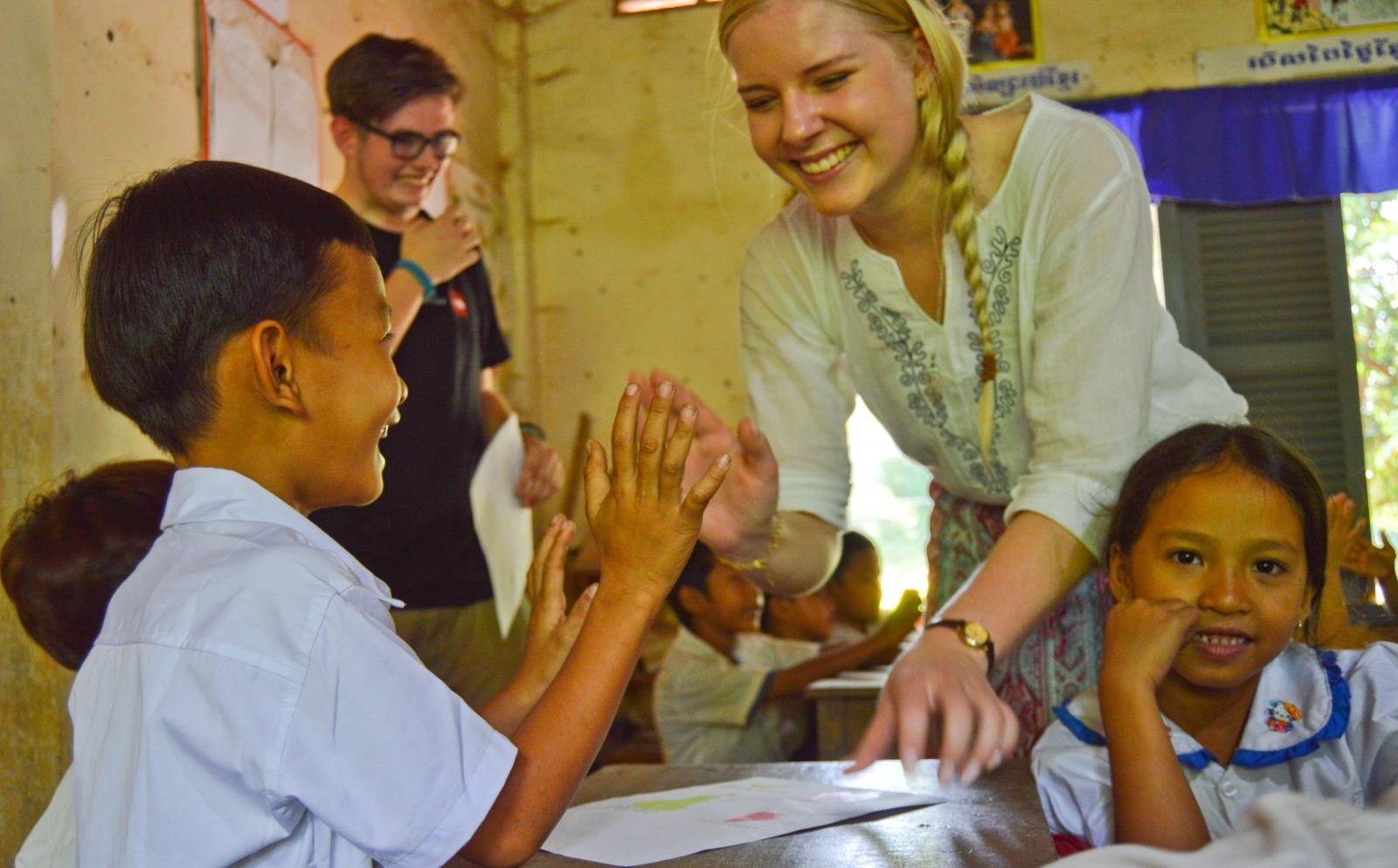 A female volunteer gives a child feedback while teaching abroad after she booked a trip overseas with us.