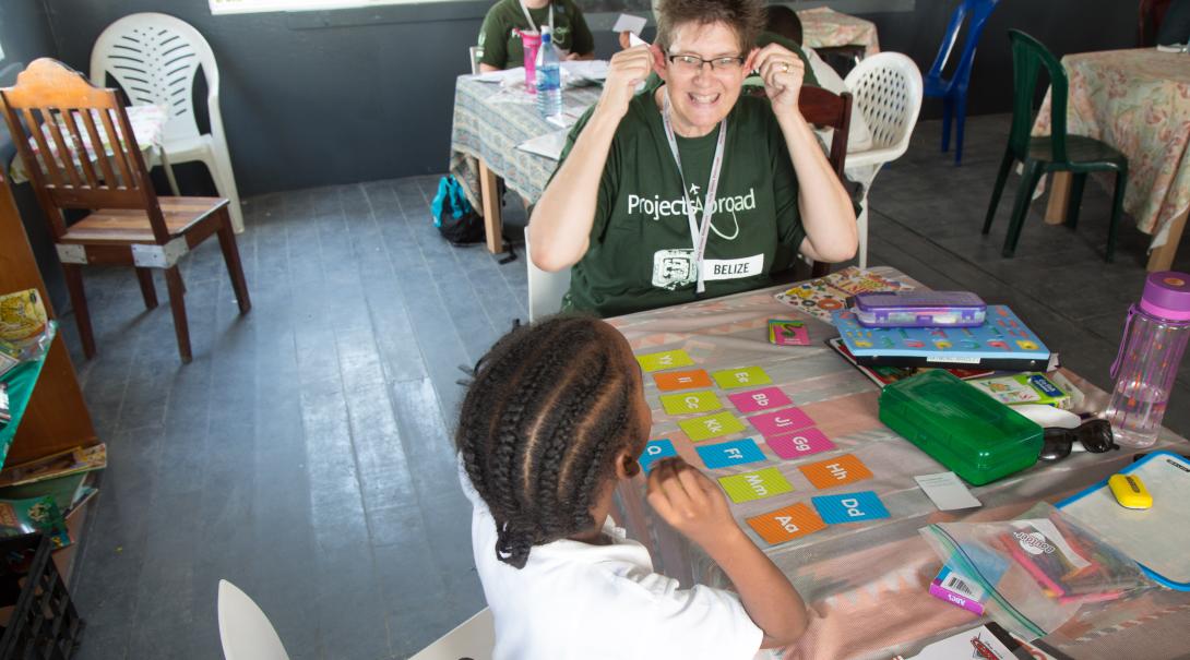 A teaching volunteer taking a career break, works with a student in Belize to improve her literacy